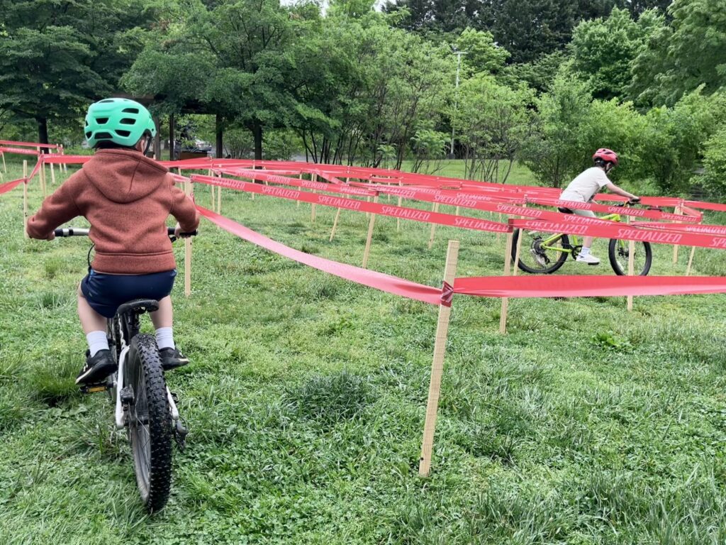 child rides bike in obstacle course on green grass
